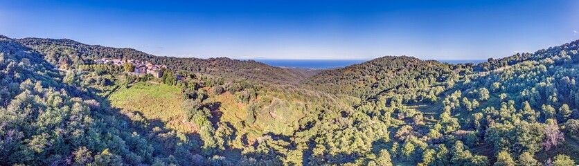 Aerial panorama of a traditional Corsican mountain village with views of the dramatic eastern coastline
