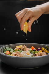 Fresh lemon juice squeezed over a nutritious tuna salad with poached egg, greens and vegetables