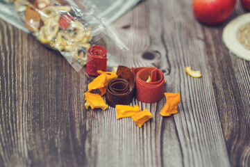 Freshly rolled, homemade fruit leather and dried fruit slices made from organic ingredients are displayed on a rustic table