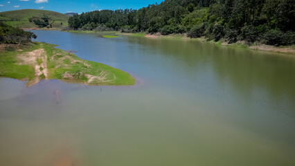 Visto de cima a represa e rodovia coma pontes altas e a natureza ao redor com lindo ceu azul.