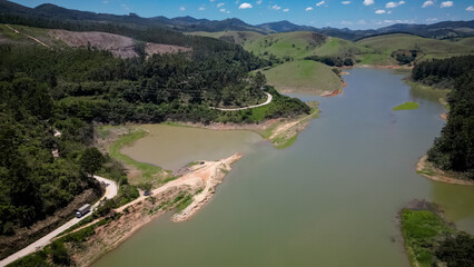 Visto de cima a represa e rodovia coma pontes altas e a natureza ao redor com lindo ceu azul.