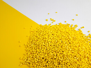 Yellow masterbatch granules on a white and yellow background, a color pigment carrier polymer in...