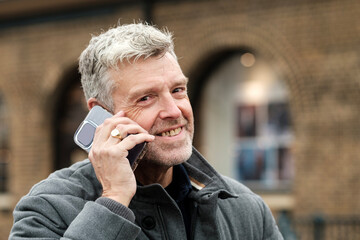 Smiling senior man talking on smartphone in urban setting