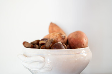 antique white ceramic bowl with chestnuts and sweet potatoes on white wall