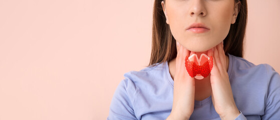 Young woman checking thyroid gland on color background, closeup