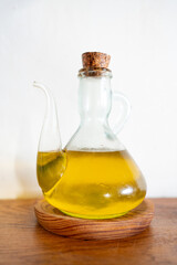 Typical Catalan oil cruet with virgin olive oil on a wooden plate on a wooden surface. Traditional utensil for making sauce and bread with tomato.