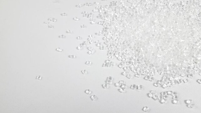 Virgin polycarbonate plastic granules are poured on a white background, one of the main materials in the plastics industry.
