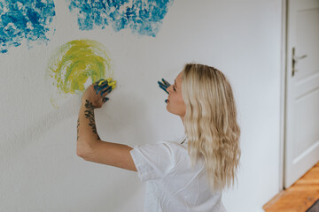 Young Woman Painting a Wall with Yellow and Blue Hand Strokes