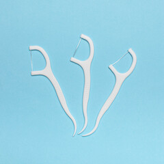 Three White Dental Floss Picks on Blue Background for Oral Hygiene Concept
