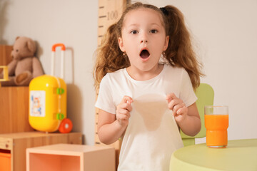 Shocked little girl spilled juice on her t-shirt at home