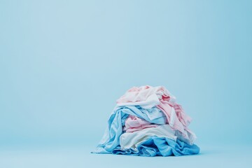 Obraz premium A vibrant still life piece depicting a crumpled mass of laundry set against a serene blue backdrop, showcasing the chaos inherent in the everyday cleaning chores we all face in our busy lives