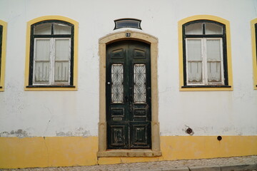 Wooden weathered old front door with mailbox with the Portuguese inscription for mail (correio), detail of a yellow and white house facade in the village of Vila do Bispo, Algarve, Portugal.