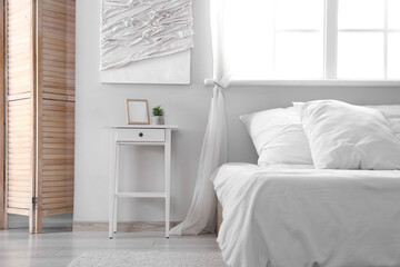 Stylish bedside table with decor near comfortable bed at home, closeup