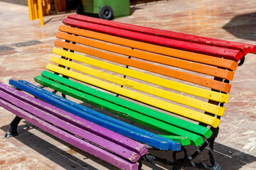 Colorful rainbow-painted wooden bench on smooth surface with background