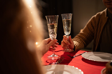 Concept for valentine's day or date. Romantic dinner for couple. Man and Woman hold glasses of Champagne.