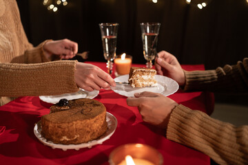 Couple having romantic dinner eating chocolate cake while sitting at home on Valentine's Day