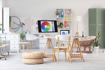 Interior of graphic designer's office with workplace, armchair and plants