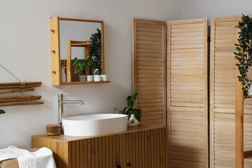 Interior of light bathroom with sink, mirror and folding screen