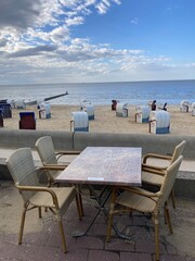 Terrasse mit Tisch und Stühlen, an der Strandpromenade am Strand von Cuxhaven in der Nordsee mit Blick auf das Meer