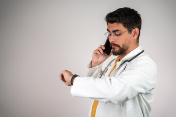 Male doctor checking his watch, professional healthcare provider in uniform, focused on time management in a medical environment, ready for the next patient or task.