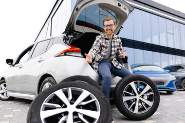 Naklejka premium Car mechanic working in car showroom and changing wheel alloy tire. Repair or maintenance auto service.