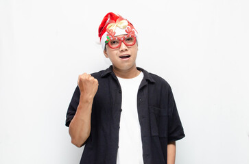 happily attractive young asian man wearing santa claus hat and christmas glasses dancing and celebrating christmas. christmas and holiday concept.