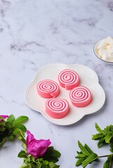 Jelly candies made of colored jelly and white marshmallow, twisted into a roll, on a light plate on a light background. Sweets, gifts.