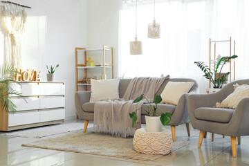 Obraz premium Interior of light living room with grey sofa, armchair and window