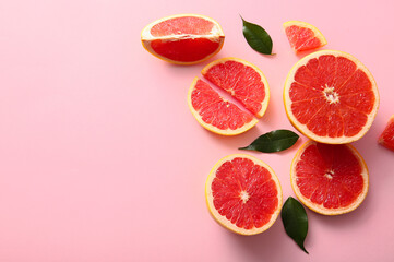 Cut fresh grapefruits and leaves on pink background