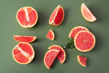 Cut fresh grapefruits on green background
