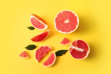 Cut fresh grapefruits and leaves on yellow background