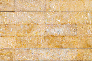 Fototapeta premium Yellow and brown stone wall with wear and tiny joints