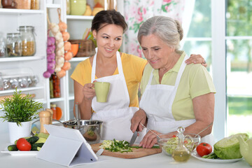 Elderly woman with her daughter cooking in the kitchen