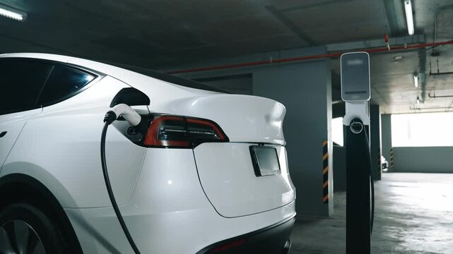 Slow motion EV electric car recharge at shopping center indoor parking lot charging in downtown city showing urban sustainability green clean rechargeable energy lifestyle of electric vehicle innards