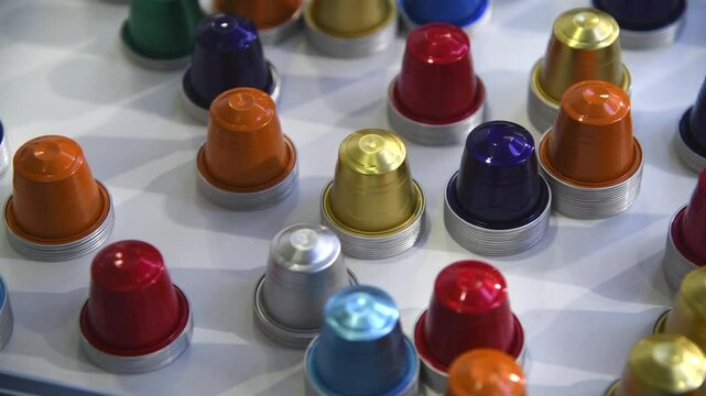 Close-up view of group of various multi coloured empty aluminium packages for coffee capsules (or coffee pods) lying on grey table. Coffee tool background. Copy space. Recyclable material theme.
