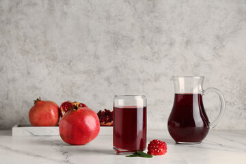 Glass and jug of fresh pomegranate juice on white background