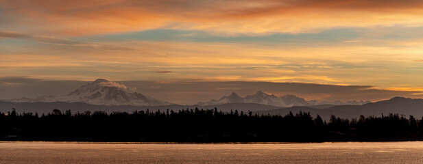 Mt. Baker during a colorful and dramatic sunrise looking across Hale Passage in the Salish Sea area of western Washington state. Seen from Lummi Islands east side during the minutes before sunrise.