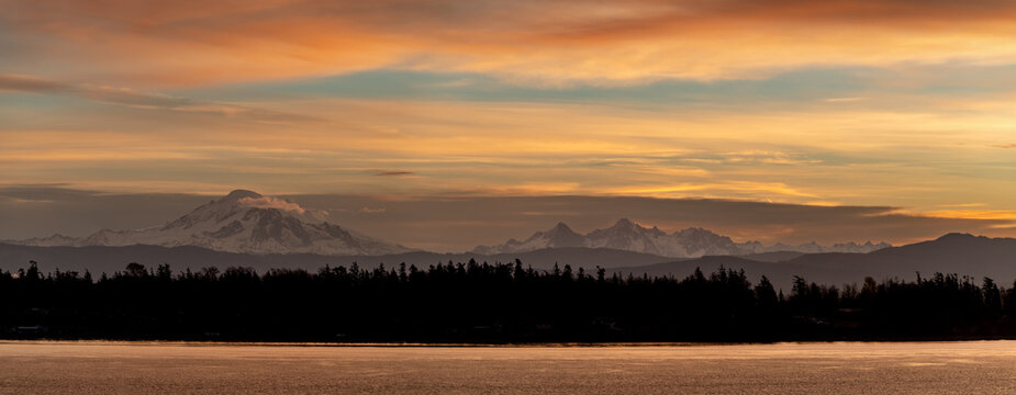 Mt. Baker during a colorful and dramatic sunrise looking across Hale Passage in the Salish Sea area of western Washington state. Seen from Lummi Islands east side during the minutes before sunrise.