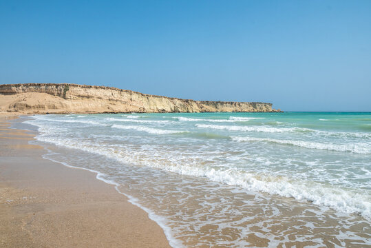 A beach with a cliff and waves crashing on the sand, Qeshm, Iran