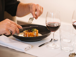 a man eating a plate of salmon tartare in a restaurant