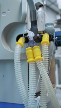 Thick tubes attached to the artificial lung ventilating machine. Low angle view on the modern medical equipment in surgery room. Vertical video.