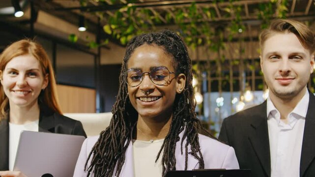 Multiracial team of business professionals stands in a row, smiling confidently for a corporate portrait, showcasing unity, leadership, and professional camaraderie.