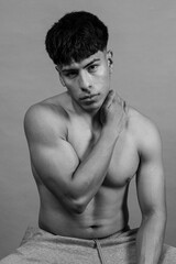 Fototapeta premium Shirtless hispanic fitness model sitting and showing his muscles