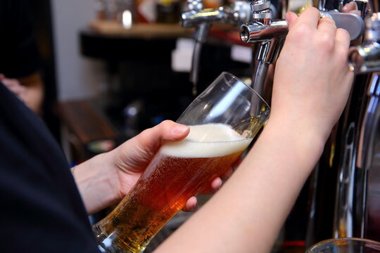 A skilled bartender is expertly pouring a delicious craft beer from the tap at a local bar