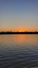 Fototapeta premium Sunset Over River with Silhouetted Cityscape and Monument