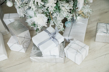 Beautiful Christmas gift boxes on floor near fir tree in room. Traditional christmas pine tree with holiday decorations,Warm living room decorated with Christmas accessories.