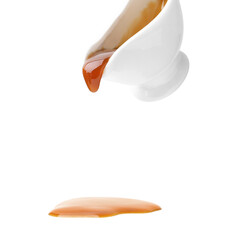 Tasty caramel sauce dripping from gravy boat on white background, closeup