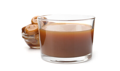 Tasty caramel sauce in glass bowl and candies isolated on white