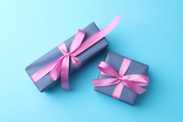 Gift boxes with bows on light blue background, flat lay