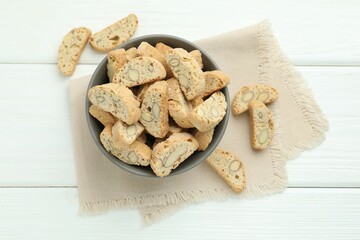 Traditional Italian almond biscuits (Cantucci) in bowl on white wooden table, top view